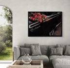 A framed wall art print depicting red roses on a black car door with the word 'Impala' visible, displayed above a gray sectional sofa in a modern living room setting.